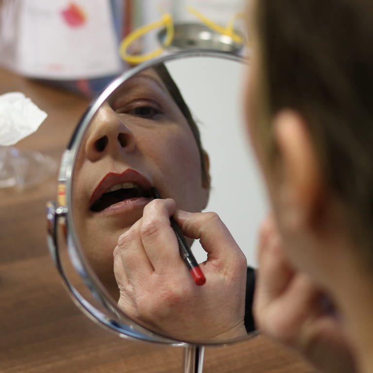 Eine Frau schminkt sich vor dem Spiegel die Lippen. (Foto: SWR)