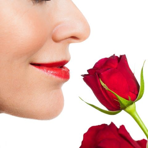 Eine Frau riecht an einer roten Rose. Düfte lassen sich unendlich kombinieren